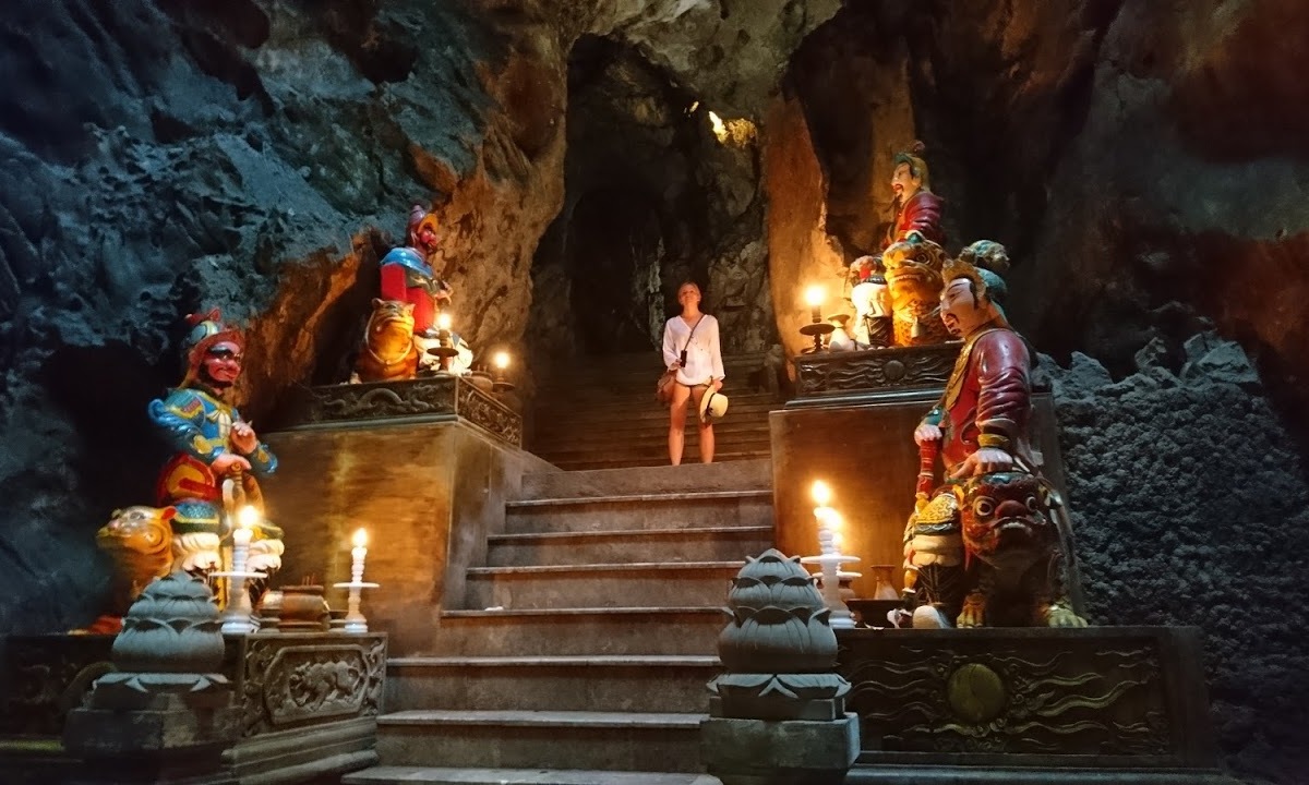 Aga standing on a stone staircase, illuminated by candles and decorated with colorful statues