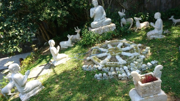 A marble statue garden - Buddha is accompanied by deers and praying monks. They all sit in a circle, around a dharmachakra wheel.